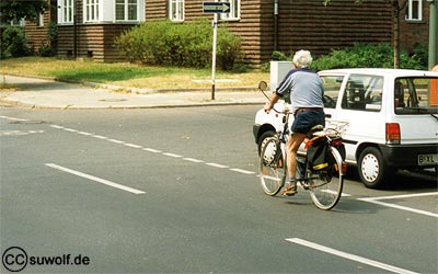 Foto: Radfahrer fährt gut sichtbar auf Radfahrstreifen vor parkenden Autos. 