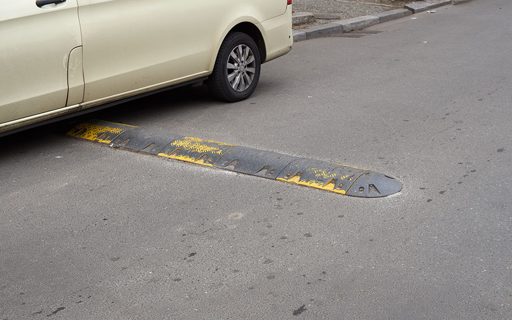 Foto: Fahrbahnschwelle mit seitlicher Vorbeifahrmöglichkeit, die durch ein Auto verstellt ist.