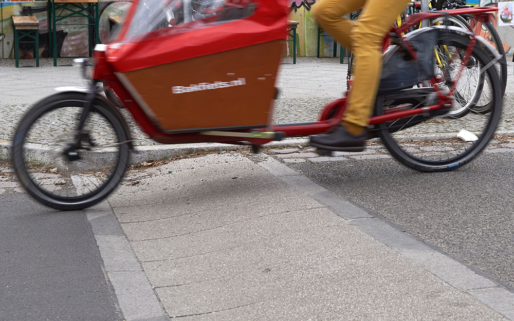 Foto: Kinderlastenrad fährt über Fahrbahnaufpflasterung.