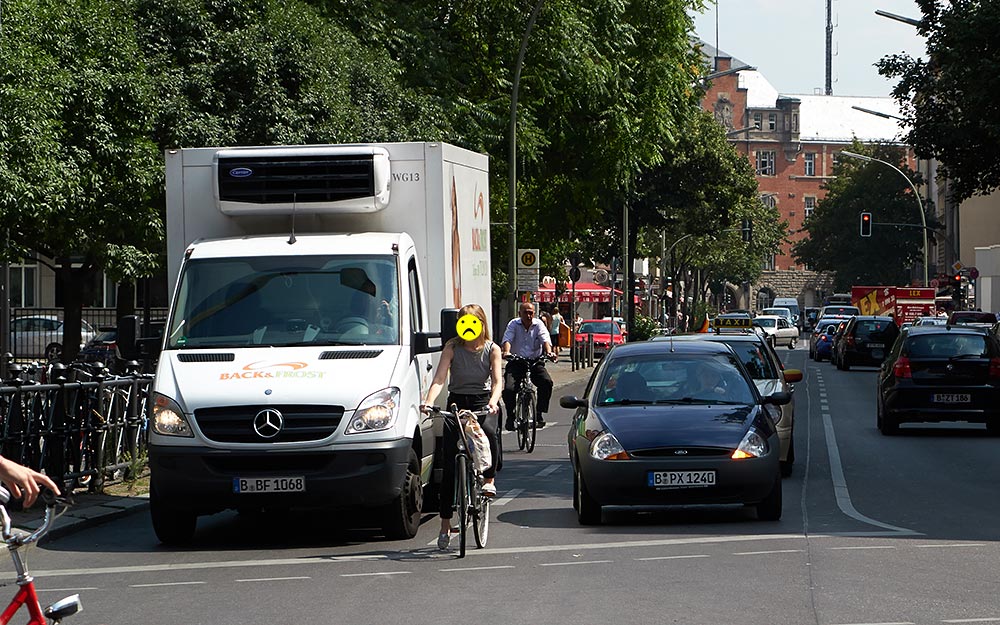 Foto: Blick von der Karl-Marx-Str. in die Erkstr. mit in der Linksabbiegespur wartender Radfahrerin.