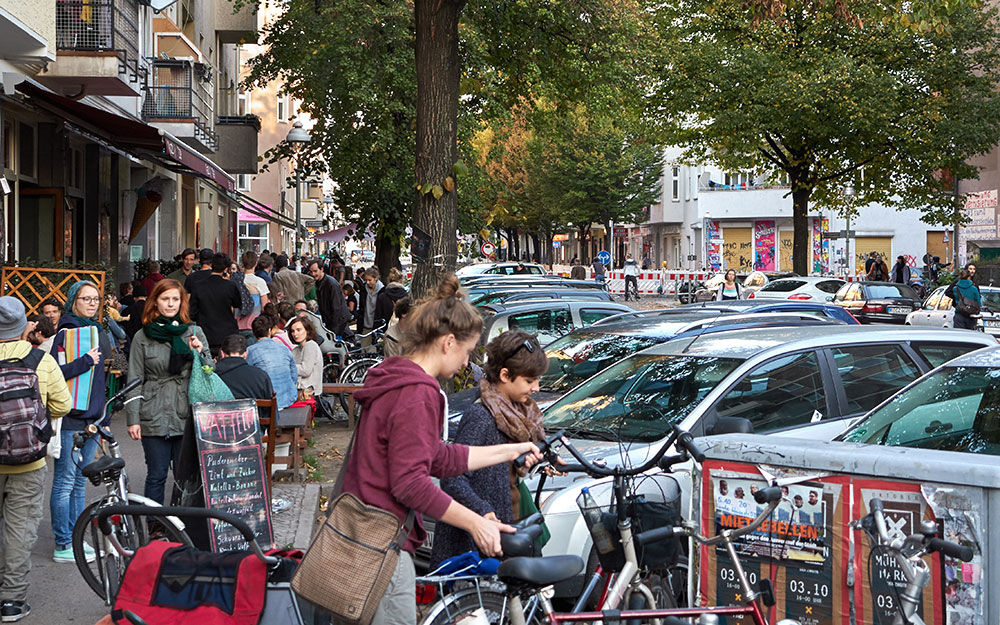 Foto: Viel Fläche für Schrägparken in der Herrfurthstr., dichtes Menschengedränge auf dem schmalen Gehweg.